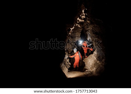 Two men, strong physique, explore the cave. Men dressed in special clothes to pass through the cave and stopped, looking at the map. Royalty-Free Stock Photo #1757713043