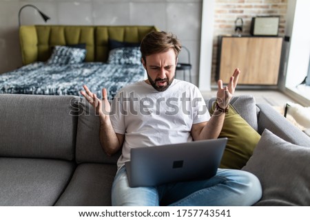 Outraged angry man reading bad news, looking at screen, having problem with broken laptop Royalty-Free Stock Photo #1757743541
