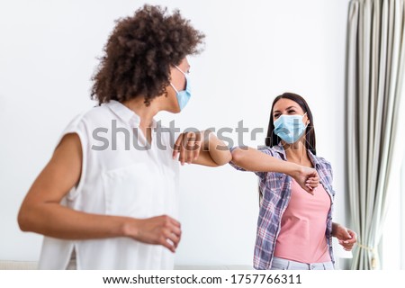 Friendly smiling millennial diverse female colleagues keeping social distance, greeting each other by bumping elbows instead of hugs or handshaking, preventing covid 19 coronavirus infection spread. Royalty-Free Stock Photo #1757766311