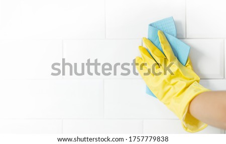 Hand and glove cleaning the bathroom tiles. Royalty-Free Stock Photo #1757779838