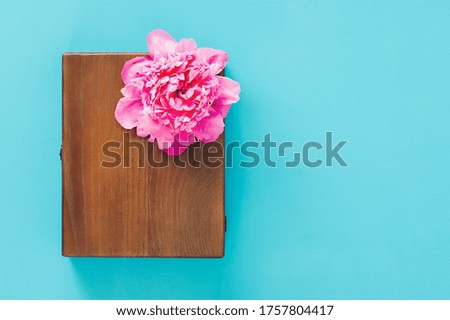 Wooden gift boxes with pink fresh peony on blue background. Craft box for storage pictures, top view, flat lay.