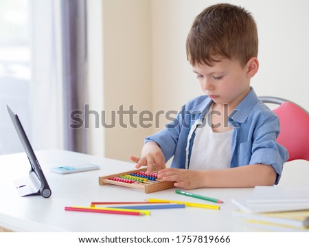 Online learning for children. Focused kid with tablet and Counting Number Frame Maths learns to count at home. Online math lesson