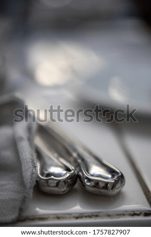 Silverware by cloth napkin on tile. Blurred dish in background.