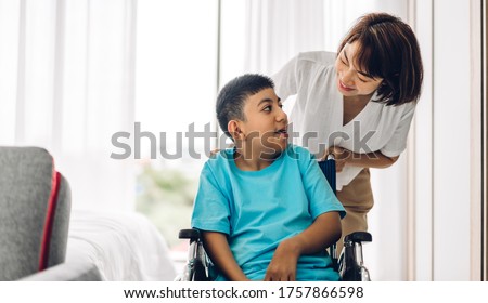 Portrait of enjoy happy love family asian mother playing and carer helping look at disabled son child sitting in wheelchair moments good time at home.disability care concept Royalty-Free Stock Photo #1757866598
