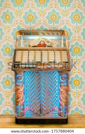 Colorful vintage jukebox in front of retro flower wallpaper on a wooden floor
