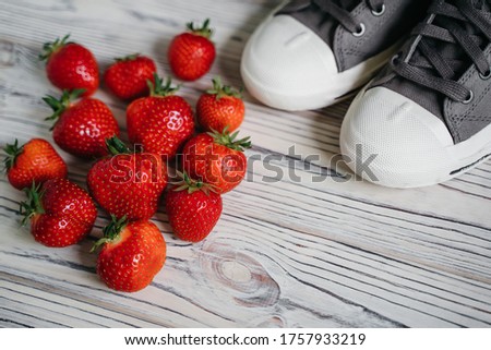  Fresh strawberries in a basket and gym shoes. High quality photo