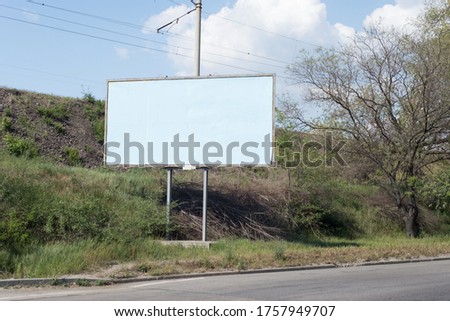 road billboard, against the background of green trees of the road, an empty ad-free billboard along the road. Advertising, signboard, blank, pattern, copy space