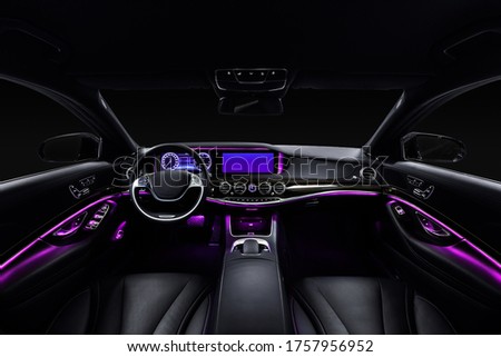 Car interior from driver seat view. Black leather cockpit with violet ambient light. Royalty-Free Stock Photo #1757956952