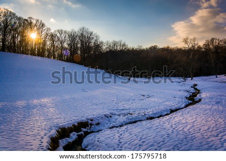 Sunset over a stream in a snow-covered field in rural Baltimore County, Maryland.