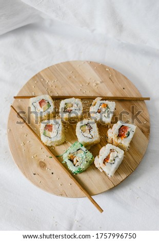
Sushi rolls on a wooden board with chopsticks on a white background. Stylish composition with sushi.