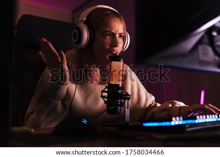 Image of displeased attractive girl expressing irritation while playing video game on computer indoors