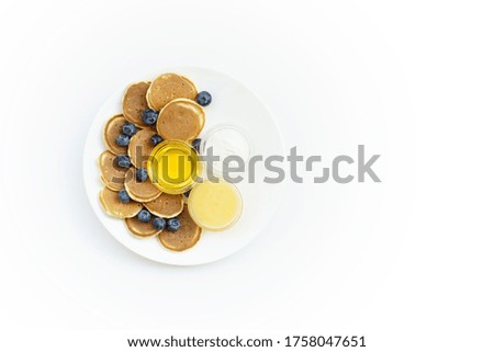 Mini Pancake cereal with honey, yogurt and blueberry on white plate. Copy space right for text.