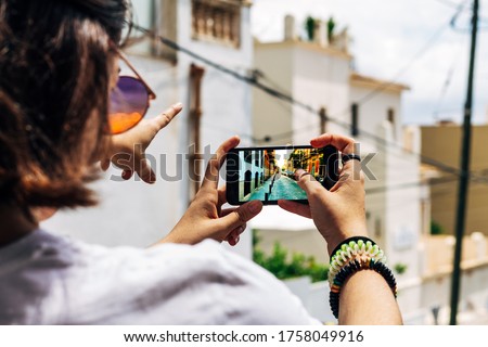 Teenager make a picture on the neighborhood at the moment her partner points where to shot. Hipster adolescent with a friend on the street.