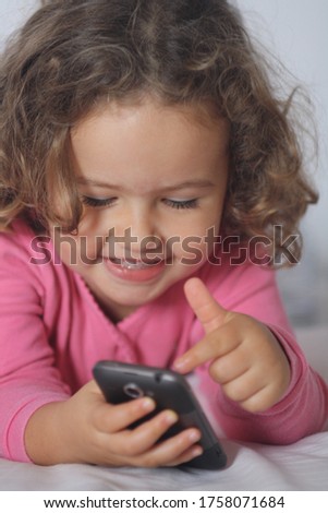 happy little girl playing with a mobile phone