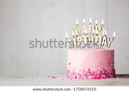Pink birthday cake with gold happy birthday candles