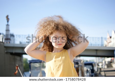 Curly girl on the pier near the river in the summer in the city