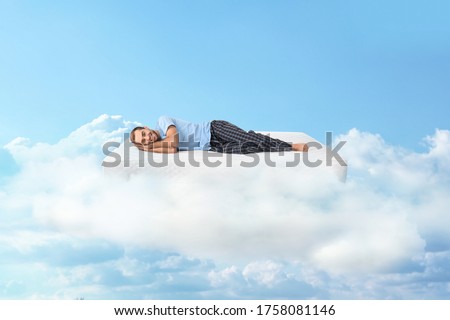 Young man lying on mattress in clouds Royalty-Free Stock Photo #1758081146