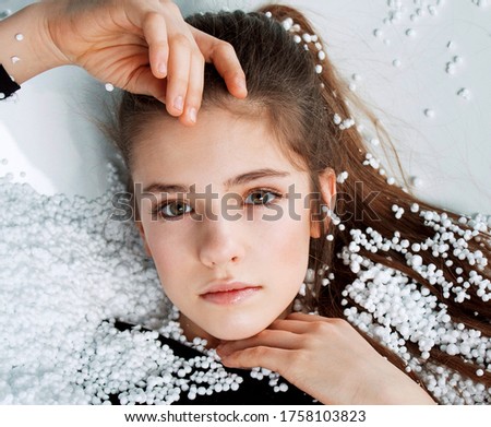 Beautiful young woman laying in a bath full of styrofoam