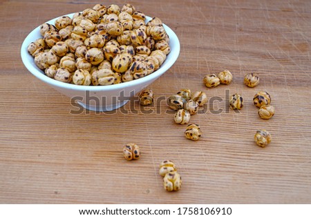Plateful of Organic Roasted spicy chickpeas and Spilled chickpeas on Wooden Background