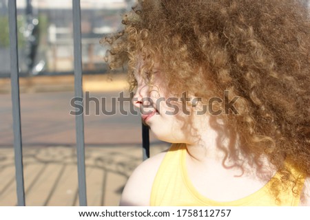 Curly girl near the fence on the river embankment