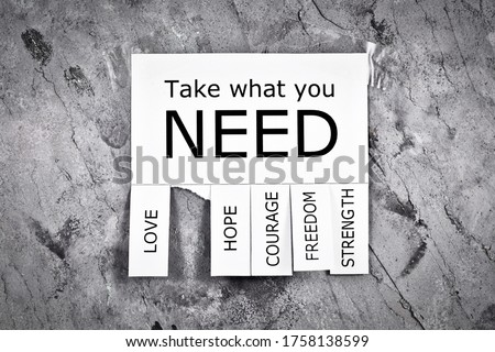 White tear-off stub note with text 'Take what you need' and words 'Love, Freedom, Hope, Courage' and 'Strength' on gray concrete wall Royalty-Free Stock Photo #1758138599