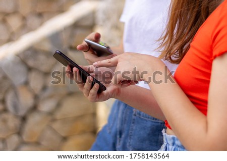 two teenage girls teaching each other social networking on the mobile phone, concept of sharing social networks and communication Digital detox.