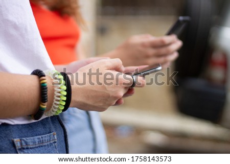 two teenage girls teaching each other social networking on the mobile phone, concept of sharing social networks and communication.