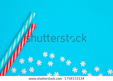 sprinkle in the form of snowflakes and cocktail straws on a blue background