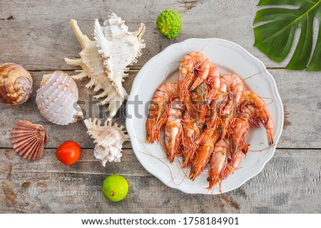 Tiger prawns or Tiger shrimps a fresh seafood on a white plate and wooden background. Top view.