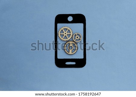 Cell phone, wooden gears on a blue background. Communication, technology.