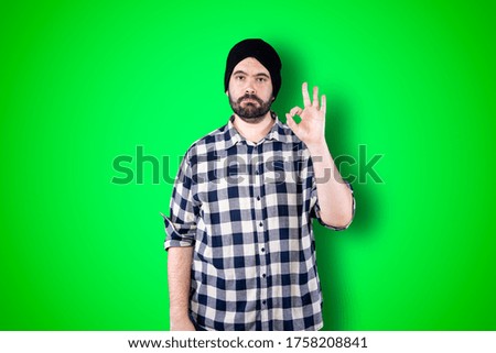 Portrait of a cheerful young man showing okay and victory gesture isolated on the chroma background