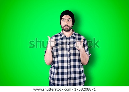Portrait of a cheerful young man showing okay and victory gesture isolated on the chroma background