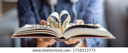 Book lover or love reading concepts. Male hand holding book with heart shape page folded. Royalty-Free Stock Photo #1758213773