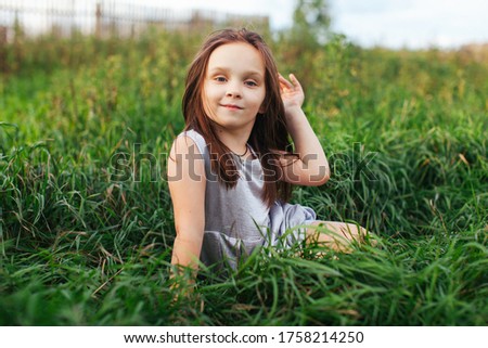 Portrait of a little girl. Beautiful girl posing in front of the camera. A girl in a dress straightens her hair.