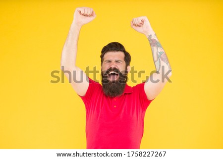 This is victory. Happy hipster with raised hands yellow background. Bearded man celebrate victory. Gambling and betting. Enjoying victory. Victory or success. Winner and champion.