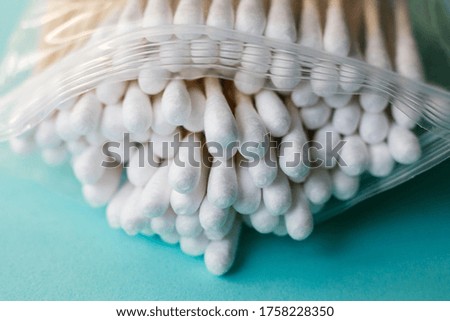 Plastic bag full of recyclable eco friendly organic cotton swabs is seen on green-blue background table 