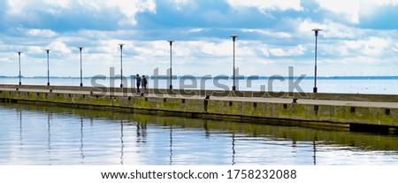 A young couple walking along the harbor.