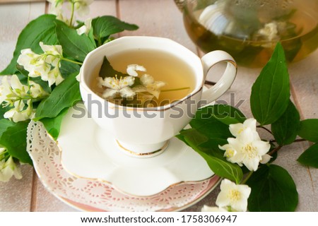 a mug of herbal tea and jasmine flowers on a white wooden table, vintage cup and jasmine flowers