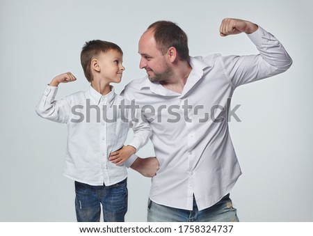 dad and son show the strength of their biceps. fatherhood, psychology of relationships.Studio, White back Royalty-Free Stock Photo #1758324737
