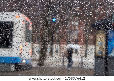 People on a bus stop on a rainy evening, blurred abstract picture with car lights.