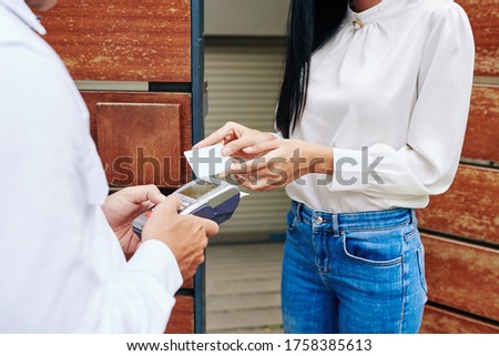 Horizontal medium close up shot of unrecognizable woman paying for food delivery service with bank card