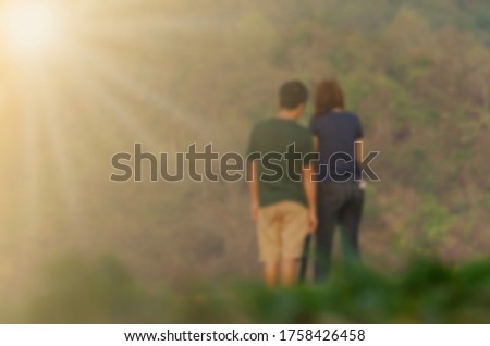 picture of a blurred lover standing on a hill in nature with a yellow light shining in the morning.