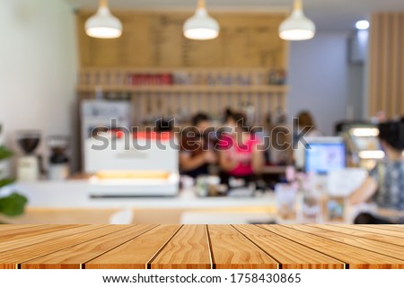 Wood table top with blur of people in coffee shop background. For montage product display or design key visual layout.