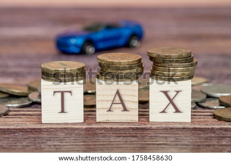 the word tax and toy car in the background, the word tax on wooden cubes, selective focus, the concept of taxation on vehicles