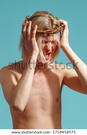 portrait of a young attractive man with long blond hair in a wreath of dry branches.