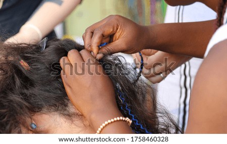 Girl braids blue African braids in a beauty salon.