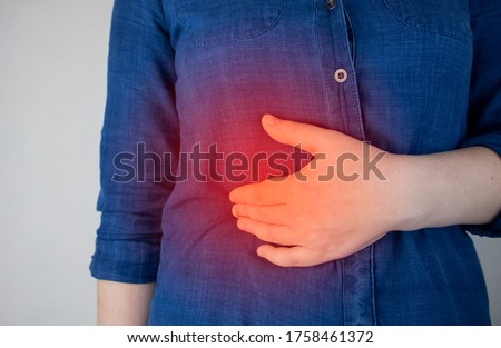 A woman grabs his right side under the ribs. Pain in the liver. Pain syndrome in liver disease. Hepatologist examination Royalty-Free Stock Photo #1758461372