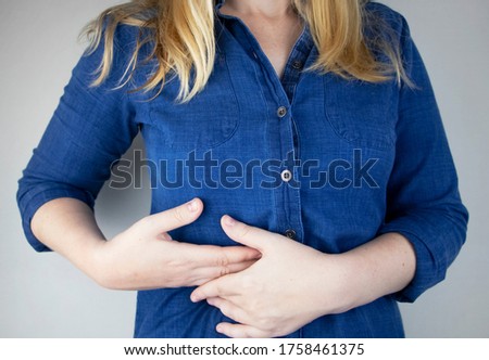 A woman grabs his right side under the ribs. Pain in the liver. Pain syndrome in liver disease. Hepatologist examination Royalty-Free Stock Photo #1758461375