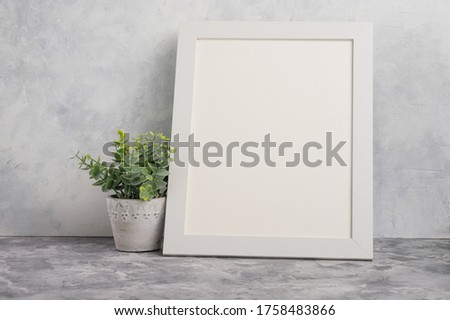 Mock up for design or logo placement of prints and fonts, white blank frame on a light wall background.