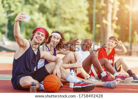 Team of basketball players taking selfie together after training at outdoor arena, copy space
